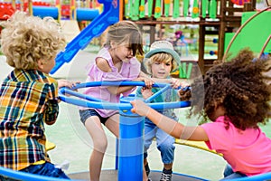 multiethnic group of little kids riding on carousel