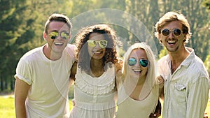 Multiethnic group of people in sunglasses smiling cheerfully, waving hands