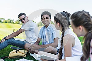 multiethnic group of teenage students smiling each other while studying together