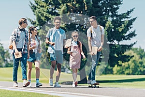 multiethnic group of teenagers talking and walking together in park