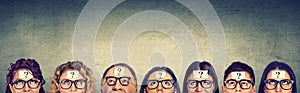 Multiethnic group of thinking people in glasses with question mark looking up
