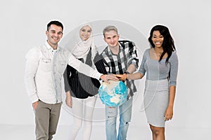 Multiethnic group of young people holding hands on the Earth globe and standing isolated on white background. Earth day