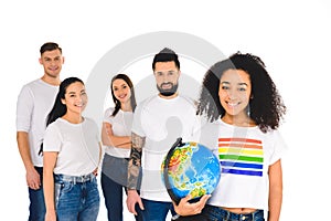 multiethnic group of young people standing behind african american woman with lgbt sign on t-shirt holding globe isolated
