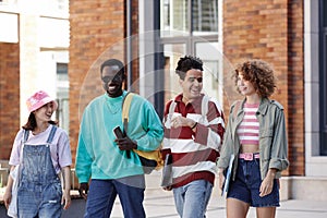 Multiethnic group of young students walking in row together and smiling