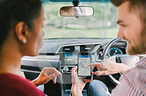 Multiethnic lover couple use navigation system on smartphone in car. Mobile phone application or crowdsourcing taxi app service