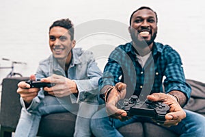 multiethnic male friends with joysticks playing video