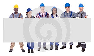 Multiethnic manual workers holding blank banner