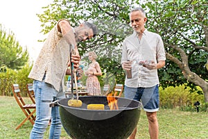 Multiethnic middle-aged people cooking with the barbecue smiling happy and laughing together. Joy concept.