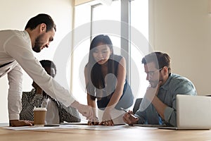 Multiethnic millennial colleagues consider paperwork at meeting