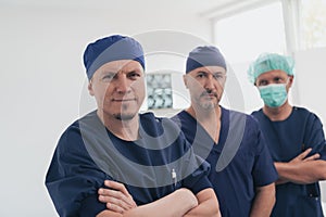 Multiethnic orthopedic doctor in front of his medical team looking at camera wearing face mask