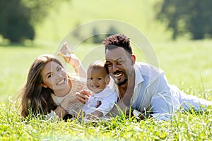 Multiethnic parents and mixed race baby in park. Multiethnic family outdoor portrait. Biracial baby child on yard