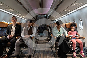 Multiethnic passengers sitting in airplane cabin during flight