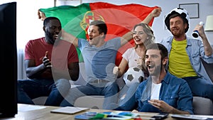 Multiethnic Portugal fans watching match at home, celebrating goal together