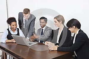 Multiethnic professionals using laptop at conference room