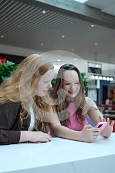 multiethnic school girlfriends using smartphone in corridor during break. Diverse schoolgirls surfing internet on mobile