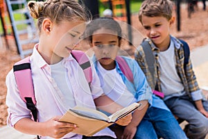 Multiethnic schoolkids reading book