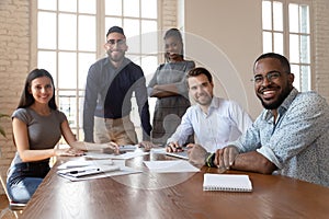 Multiethnic smiling employees gather at boardroom meeting