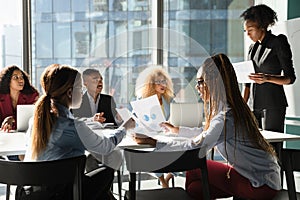 Multiethnic staff discuss sales result on briefing using paper reports