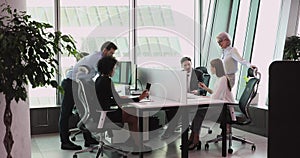 Multiethnic staff using computers talking in big office