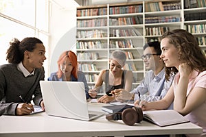 Multiethnic students convene in library involved in communication and teamwork