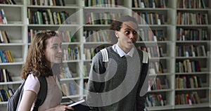 Multiethnic students greeting, hugging their friend in library