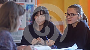 Multiethnic students study together while sitting at desk in university irrl.