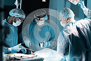 multiethnic surgeons in medical masks operating patient