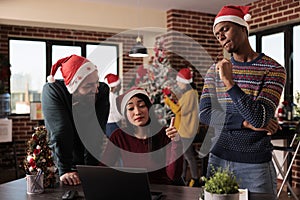 Multiethnic team of coworkers using laptop on christmas