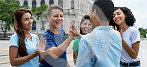 Multiethnic team of young adults give high five to friend