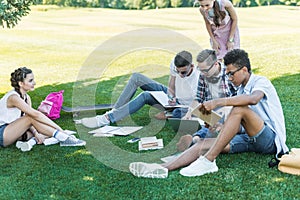 multiethnic teenage students studying with books and laptop