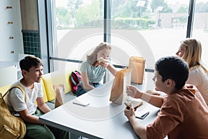 multiethnic teenagers eating sandwiches while talking