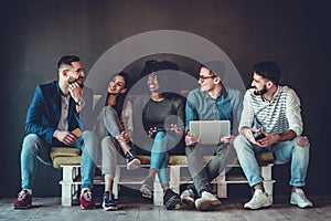 Multiethnic university students studying together. Young people working with tests and gadgets, sitting on the couch