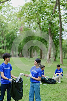 Multiethnic volunteers donate their time holding black garbage bags to collect plastic waste for recycling to reduce