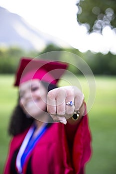 Multiethnic woman in her graduation cap and gown giving a fist pump photo