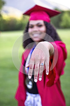 Multiethnic woman in her graduation cap and gown showing her class ring photo