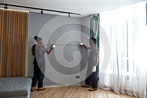 Multiethnic woman and man measuring wall to fit furniture