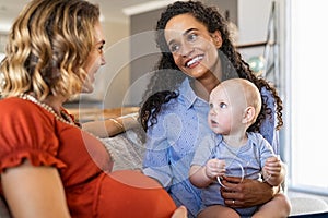 Multiethnic women friends talking and playing with child photo