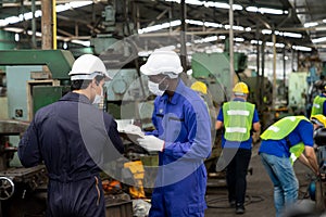 Multiethnic worker, supervisor wearing mask in manufacturing factory on business day