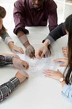 Multiethnic workers assembling jigsaw puzzle while teambuilding