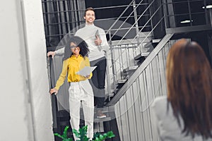 Multiethnic young businesspeople standing on staircase and smiling