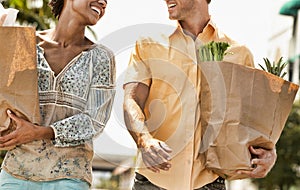 Multiethnic young couple with groceries walking outdoors