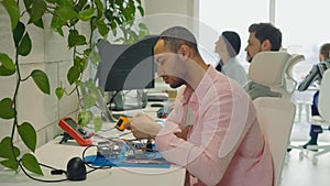 Multiethnic Young Handsome Man Measures Temperature of Welding Equipment While Sitting in Office. Concept of Electronic