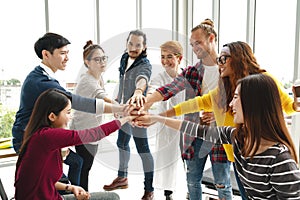 Multiethnic young team stack hands together as trusted unity and teamwork in modern office.