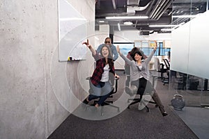 Multiethnics business team racing on office chairs