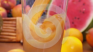 Multifruit juice is poured into a glass. Slow motion.