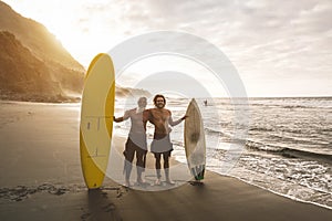 Multigeneration friends going to surf on tropical beach - Family people having fun doing extreme sport - Joyful elderly and