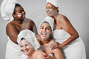 Multigeneration women with diverse skin and body laughing together while wearing body towels - Focus on center female face