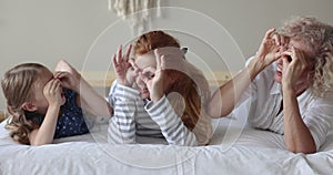 Multigenerational family staring at camera through fingers showing eyewear sign