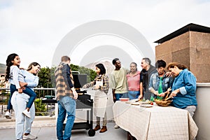 Multigenerational friends having fun doing barbecue at house rooftop
