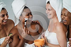 Multigenerational women having fun applying face beauty mask with cucumbers on their face - Skin care therapy - Focus on african